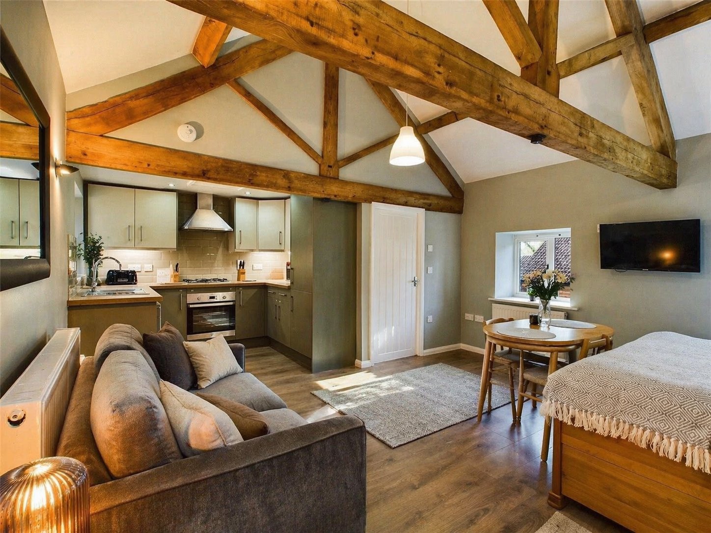 The studio: king bed, sofa, dining table and kitchen under oak beams